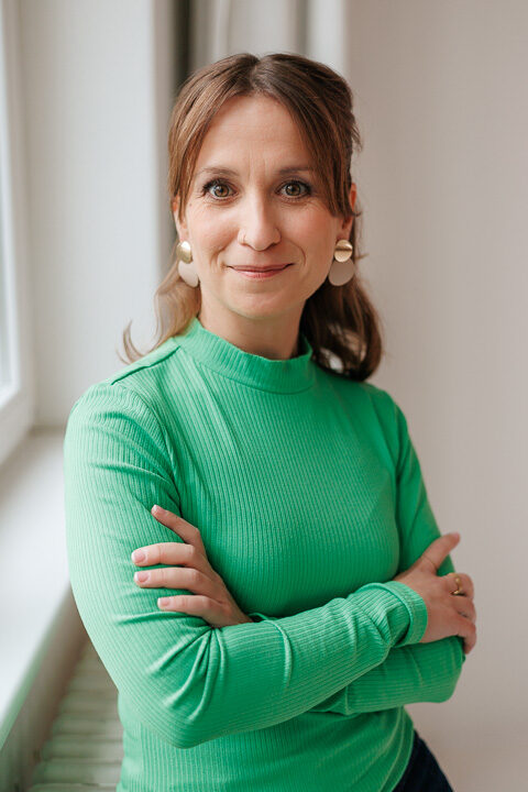 Nicole Forrai steht in einem Raum und lächelt freundlich in die Kamera.