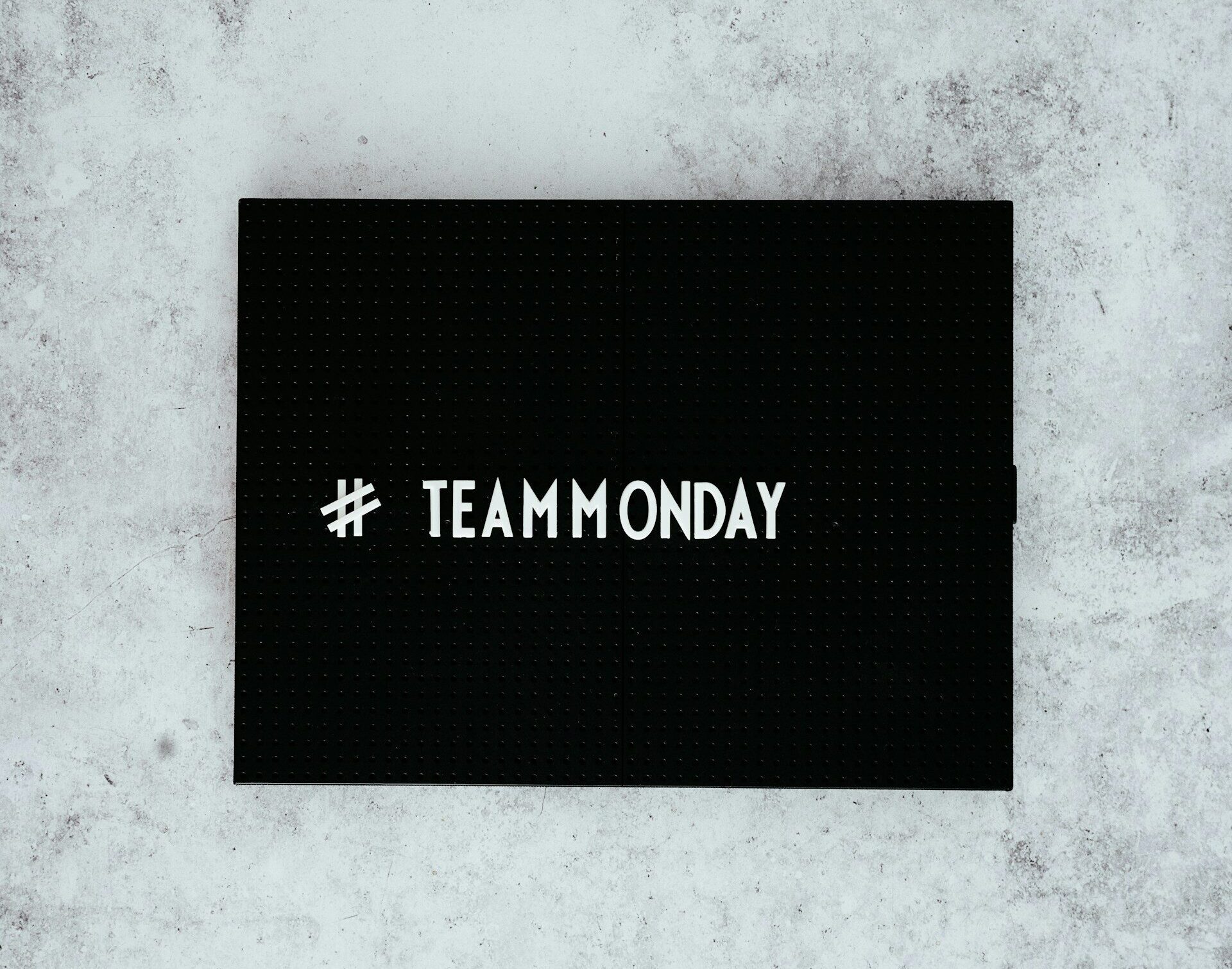 Auf dem Bild ist ein schwarzer Block zu sehen, auf dem in weißer Farbe "#TeamMonday" steht. 
